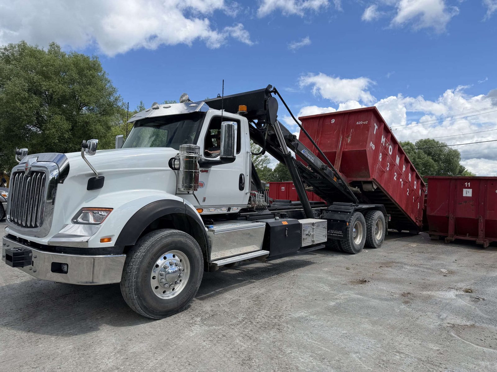Camion Transport Excavation Thompson livrant un conteneur rouge sur un chantier